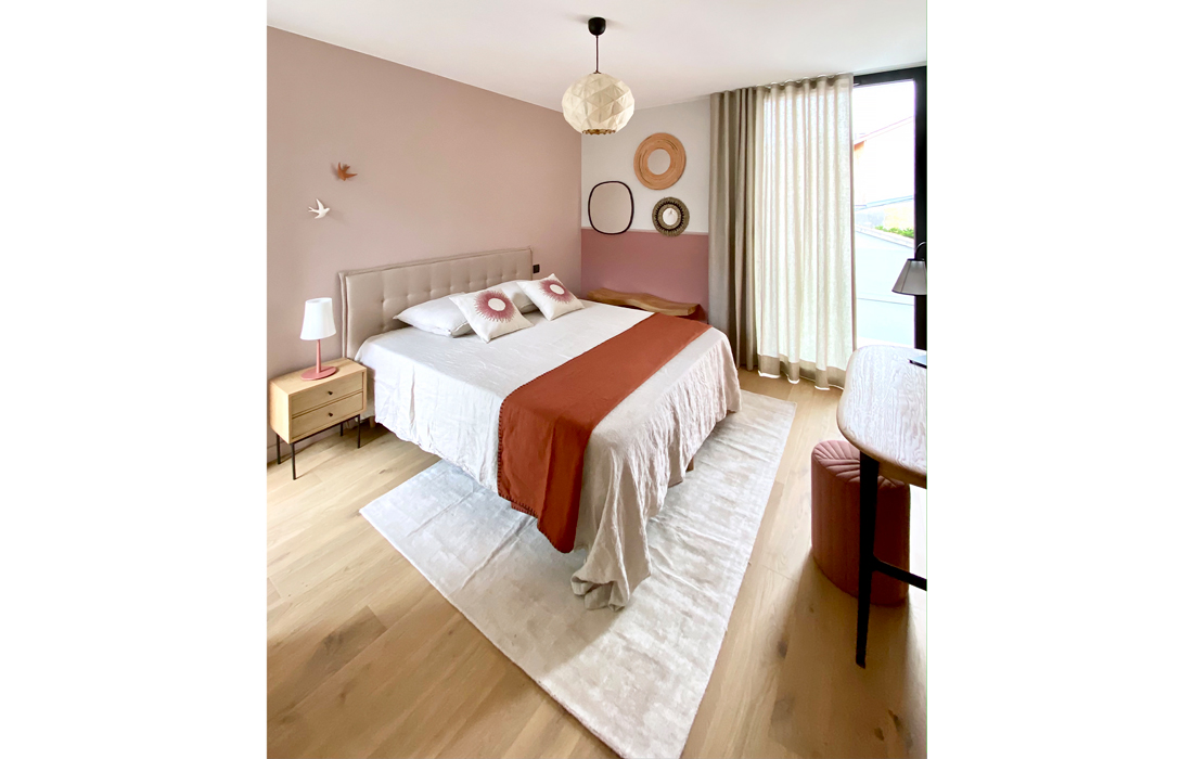 une chambre d'amis terracotta et naturelle avec des miroirs en bois rotin et metal une suspension en papier des hirondelles des draps en lin et une tete de lit beige vue d'ensemble