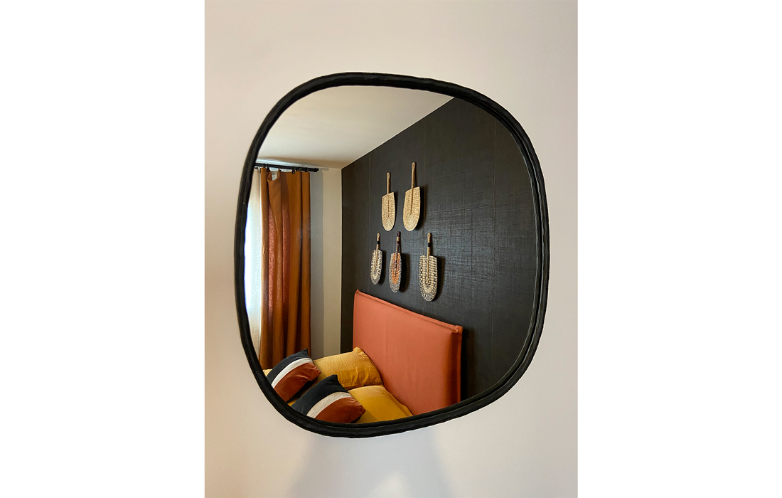 detail miroir noir martelé chambre ethnique noire ocre et orange avec lit tete de lit et evantails decoratifs