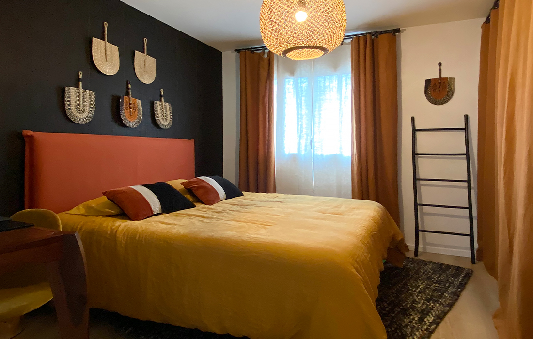 chambre ethnique noire ocre et orange avec lit tete de lit et evantails decoratifs