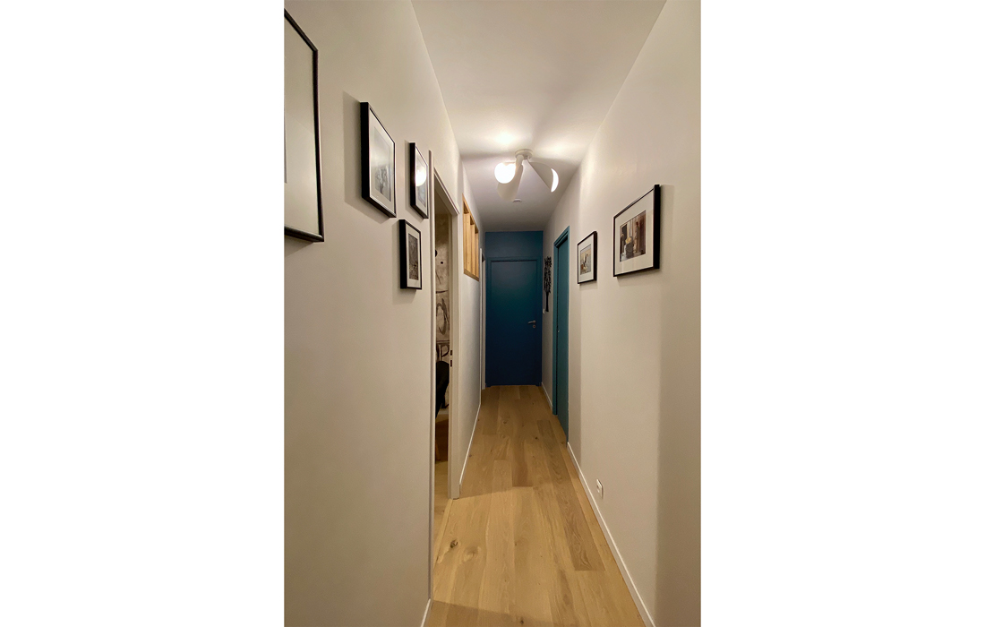 couloir avec un sol parquet des touches de peinture bleu des accessoires comme des cadres