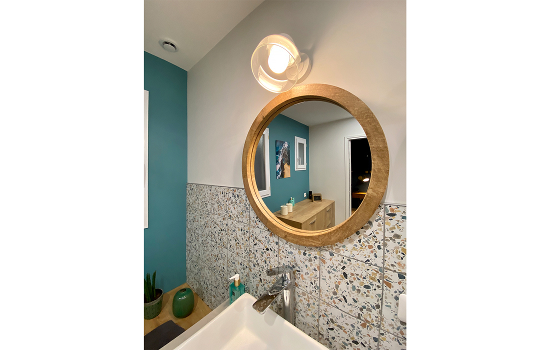 detail du miroir en bois de la salle de bain de la chambre exotique avec un carrelage en effet béton du terrazzo et des touches de bois et de peinture bleu