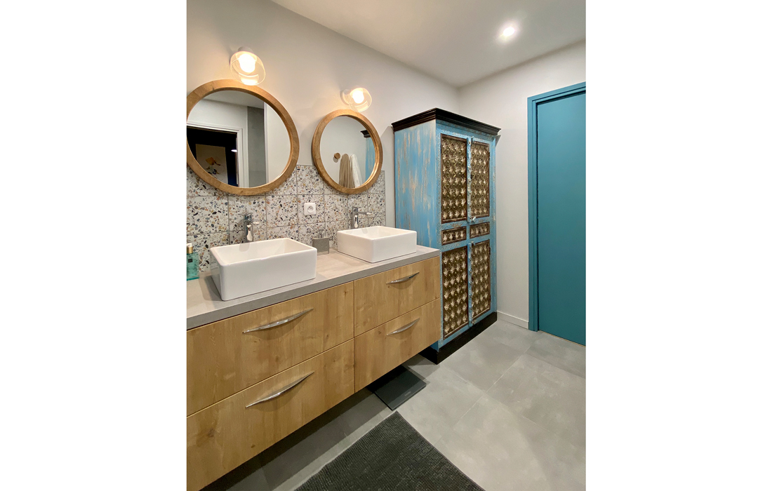 autre vue de la salle de bain de la chambre exotique avec un carrelage en effet béton du terrazzo et des touches de bois et de peinture bleu